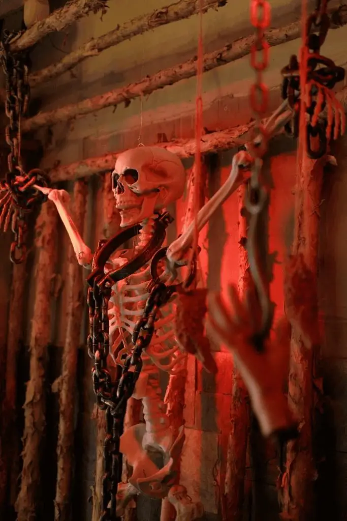 Chained skeleton bathed in red light amid twisted branches