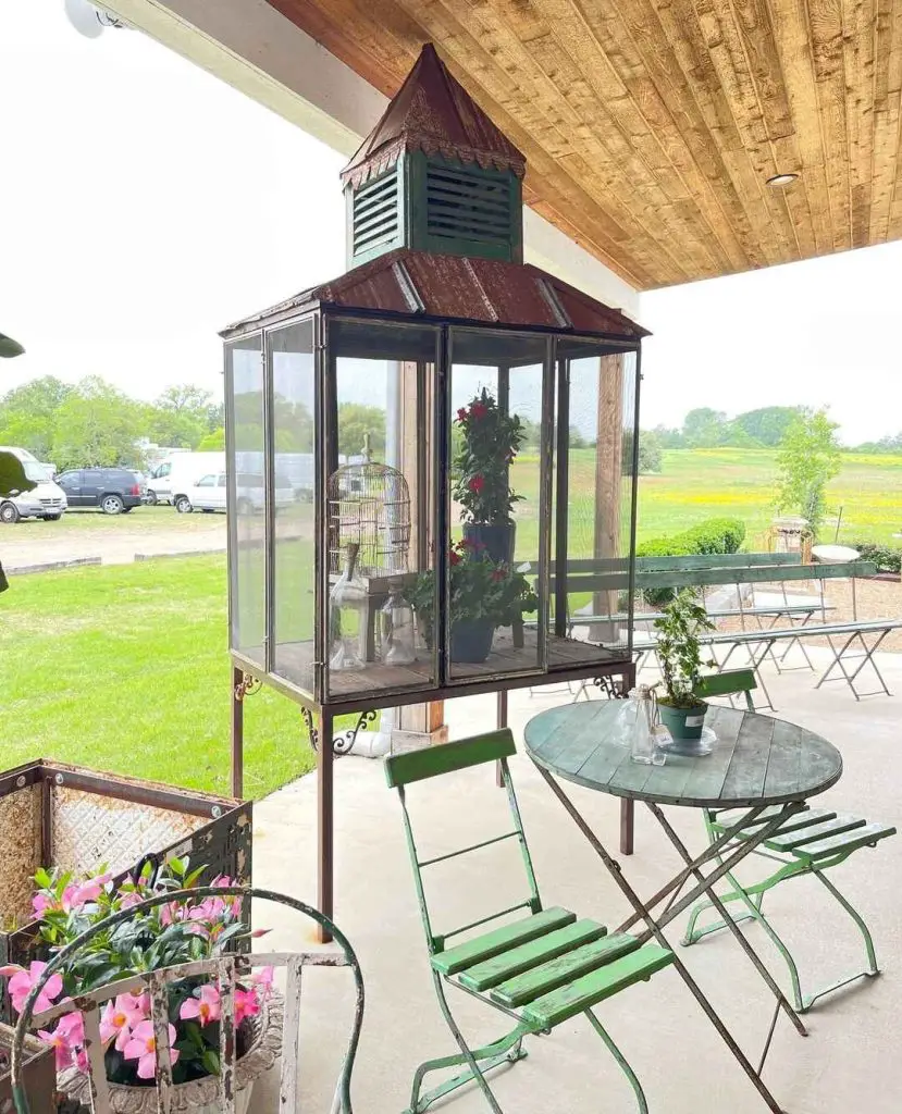 Elevated glass mini greenhouse with copper roof on patio.