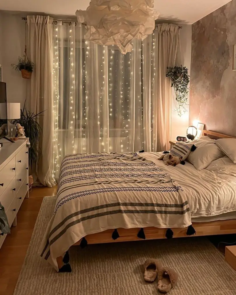 Cozy bedroom with fairy lights behind sheer curtains, striped bedding.