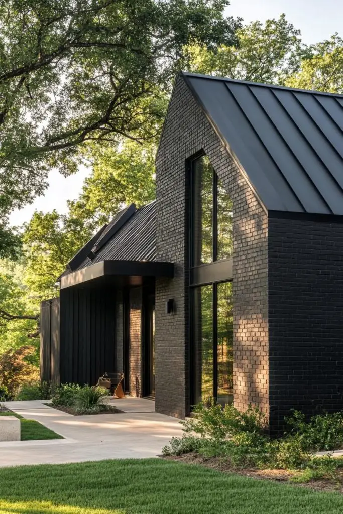 Black brick barndominium with metal roof surrounded by trees