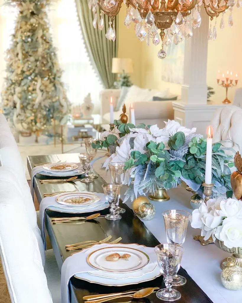 Luxurious Christmas dining table with crystal chandelier, white floral centerpiece, and gold accents