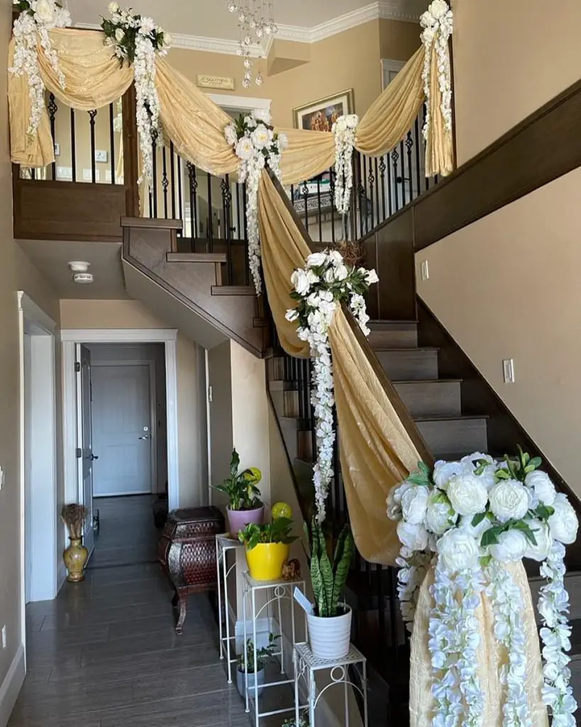 Staircase adorned with gold fabric and white flowers