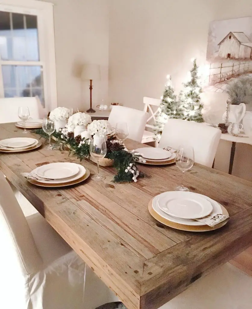 Rustic Christmas table with evergreen garland centerpiece.