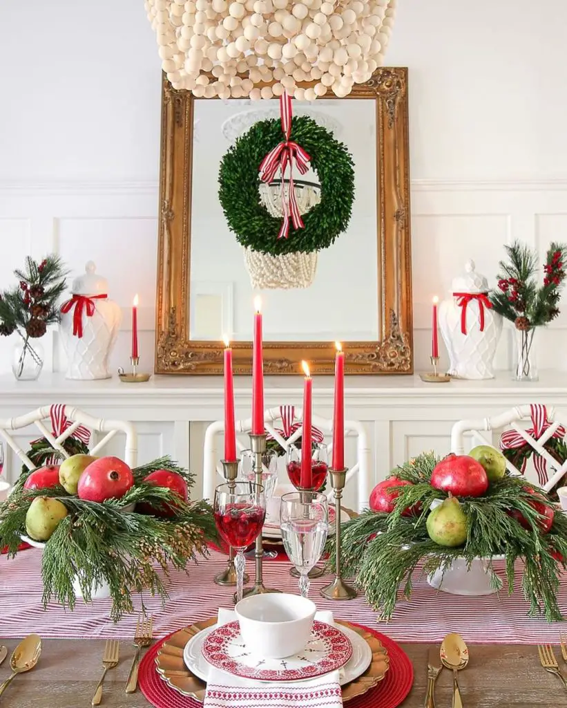 Christmas table with red candles, fruit centerpiece, and festive mantel decor.