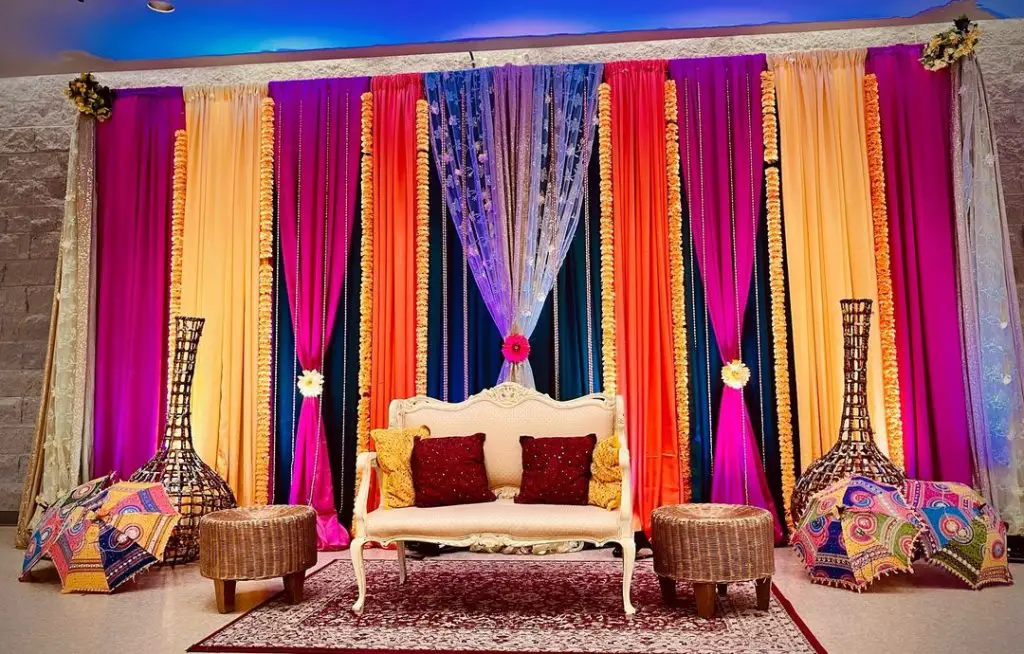 A dining area decorated with colorful curtains, white furniture and a patterned carpet.