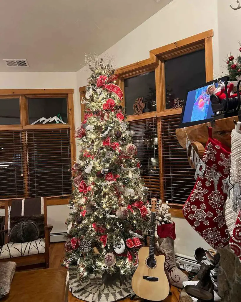 Christmas tree decorated for the holidays beside fireplace and guitar.