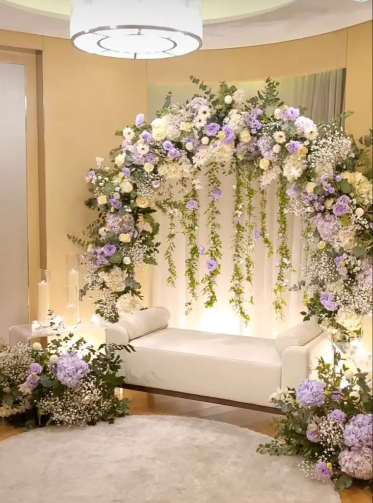 Lavender and white floral arch over wedding loveseat