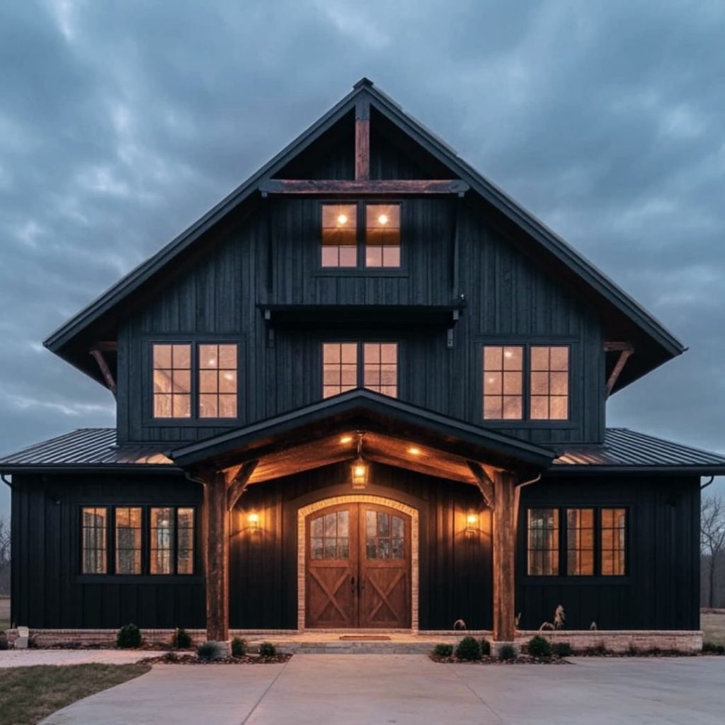 Moody black barn style home glowing warmly through windows at dusk
