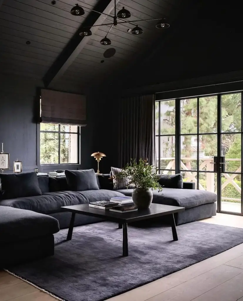 Dark living room with forest view through large windows