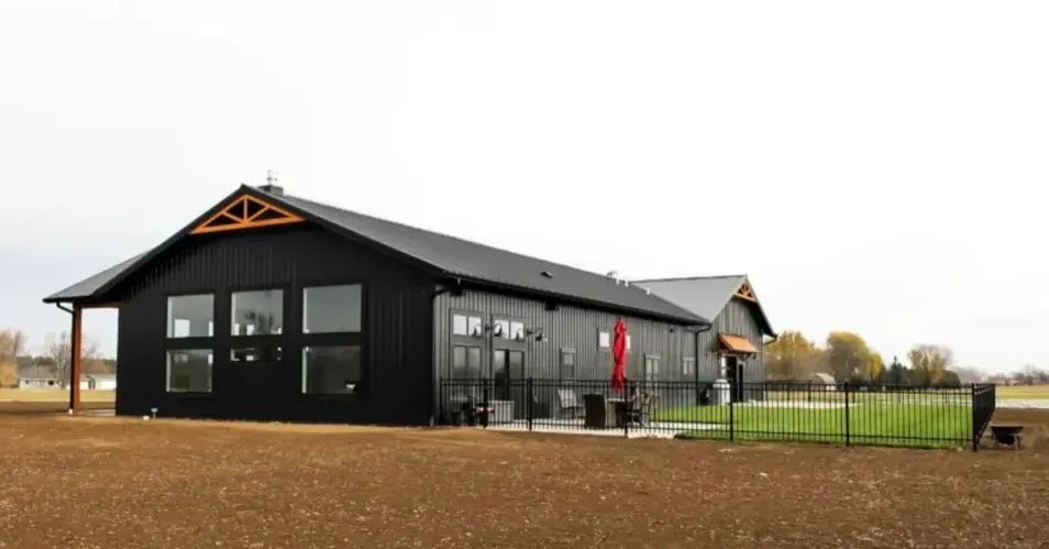 Black modern barndominium on vast prairie land