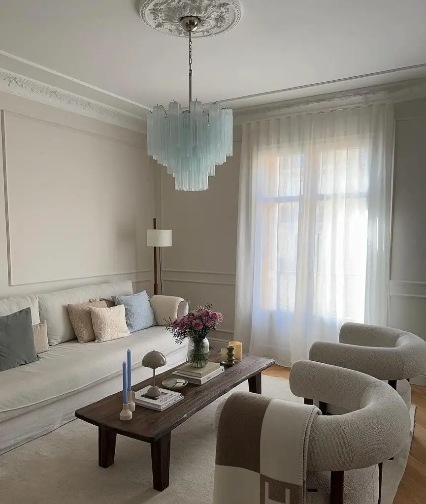  Minimalist living room with statement chandelier, neutral furniture.