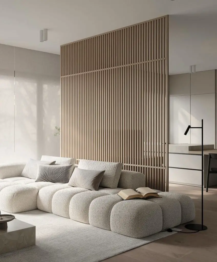 Minimalist living room with wooden slatted partition and large cream modular sofa.