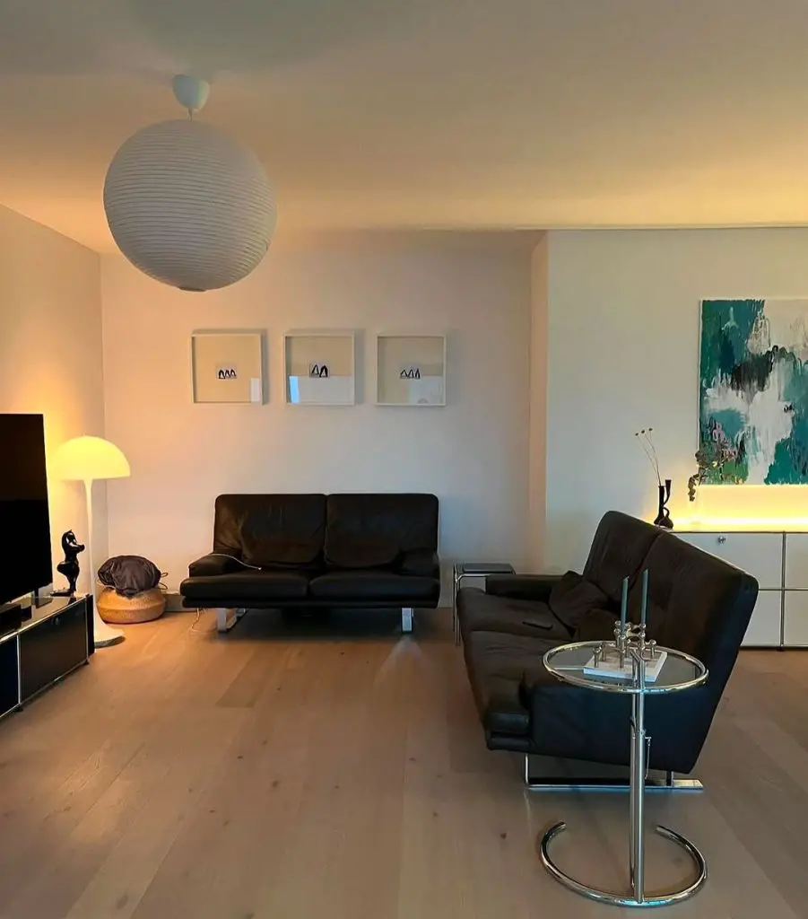 Minimalist living room with black leather furniture and abstract art.