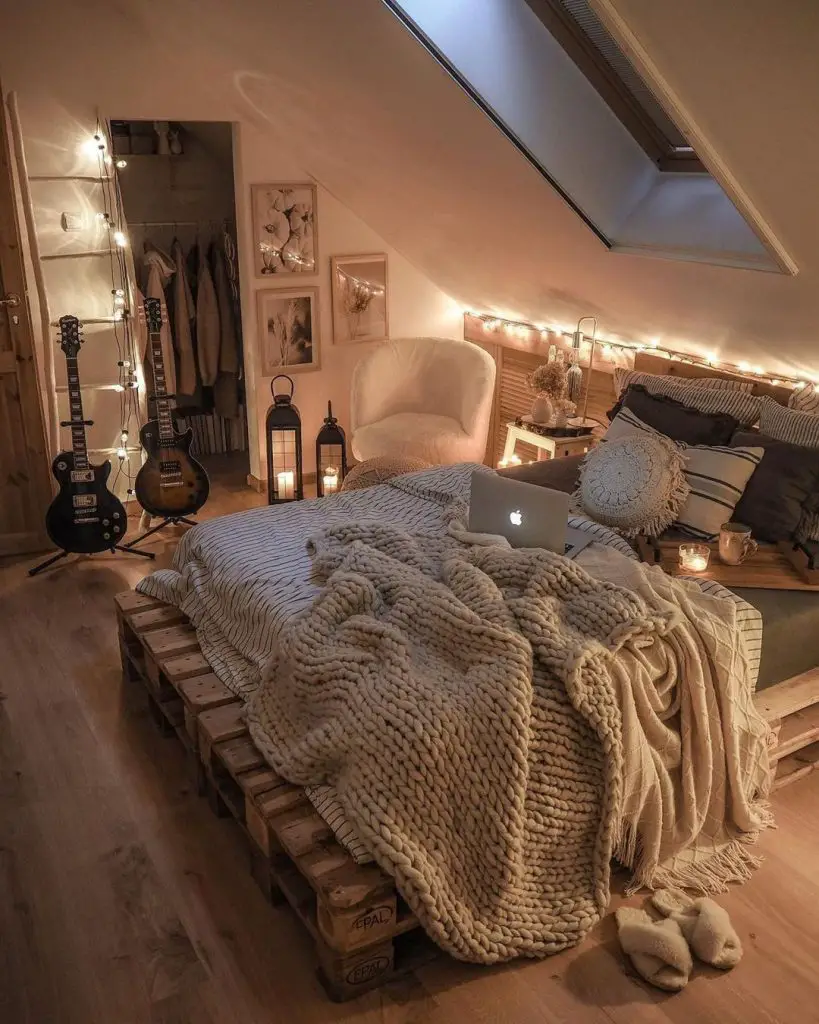 Cozy attic bedroom with pallet bed, fairy lights, guitars, and skylight.