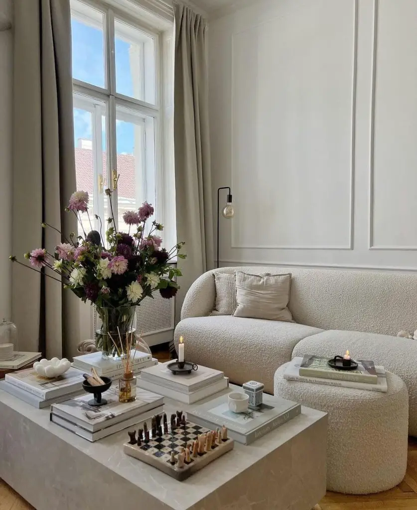  A minimalist living room with a cream boucle sofa, concrete coffee table, large window with curtains