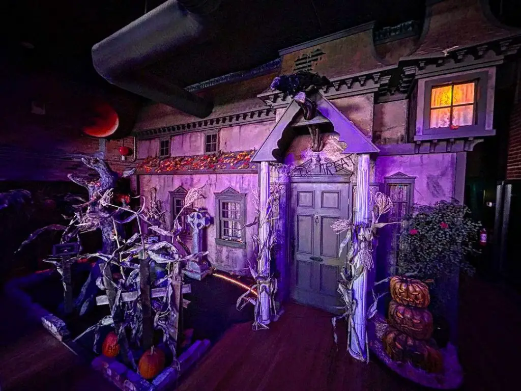 Miniature haunted house display with purple lighting and spooky decorations.