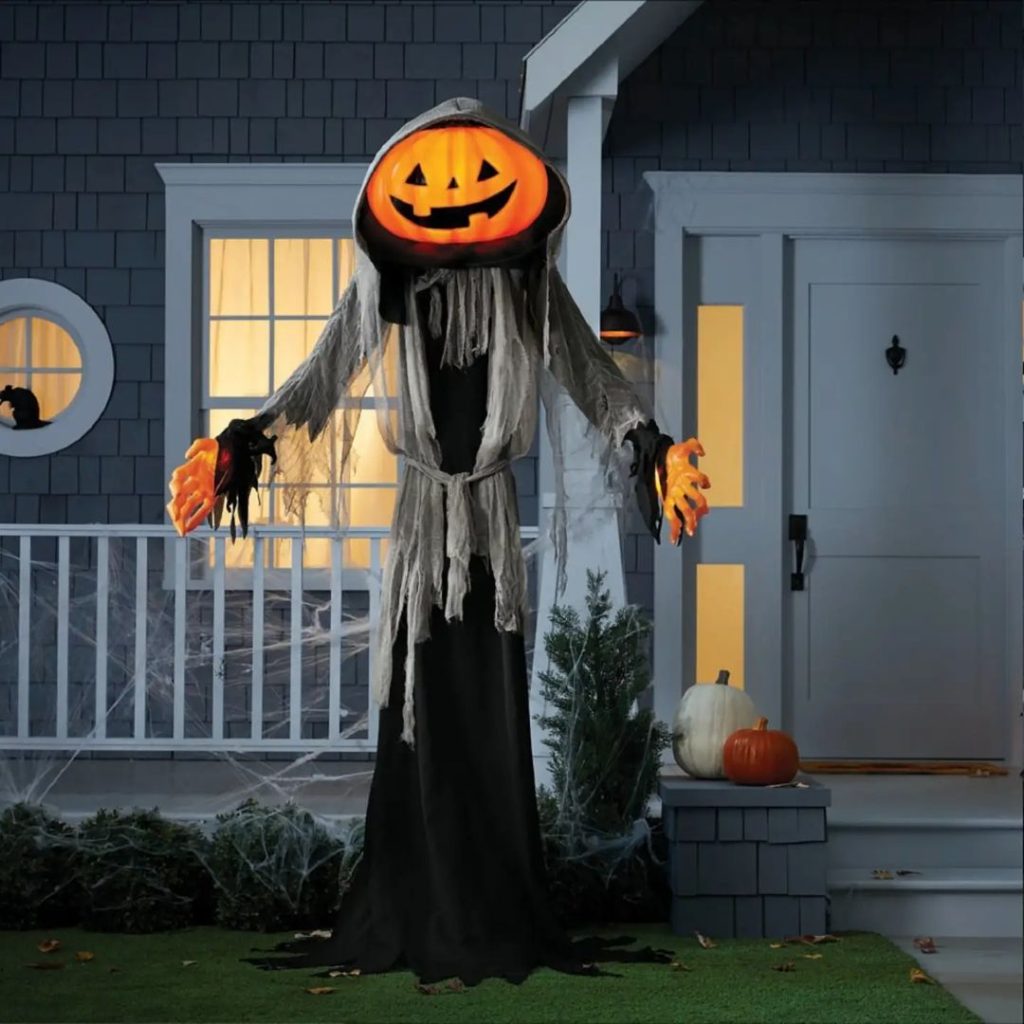 Giant pumpkin-headed ghost decoration guards house entrance.