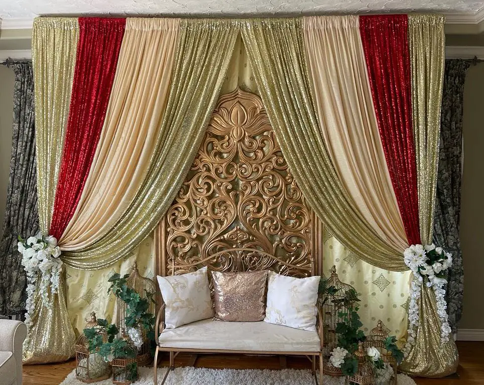 Wedding stage under golden canopy with flowers.