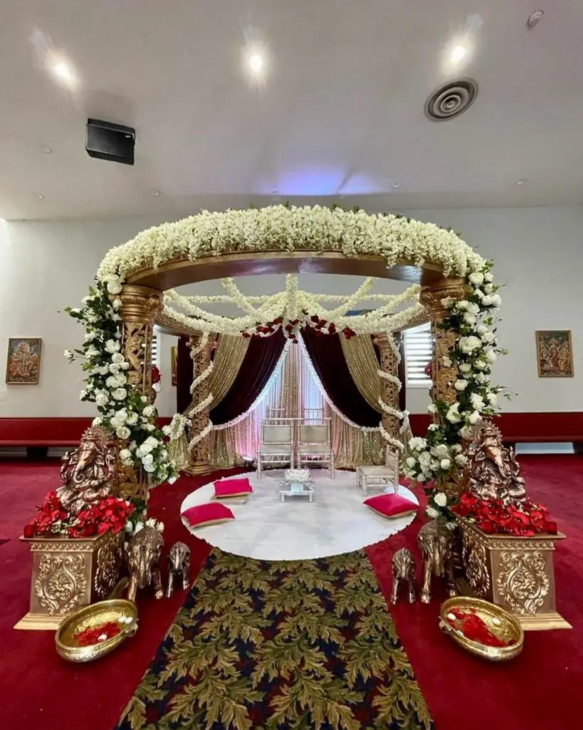 Wedding mandap decorated with flowers, lights and fabric.