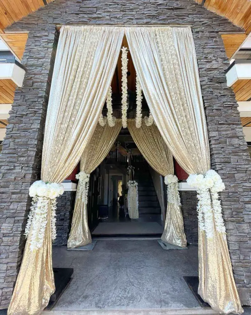 Stone archway decorated with gold curtains and flowers