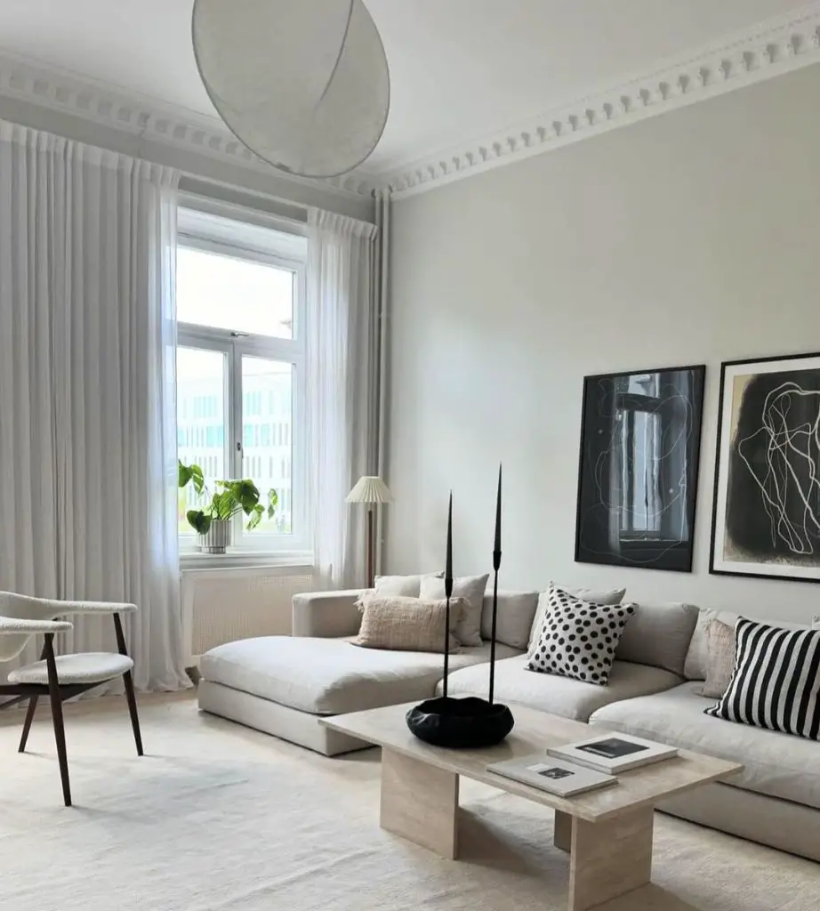 A minimalist Scandinavian living room with a grey sectional sofa, abstract black and white artwork