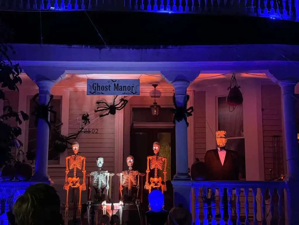 Illuminated skeletons on spooky blue-lit porch