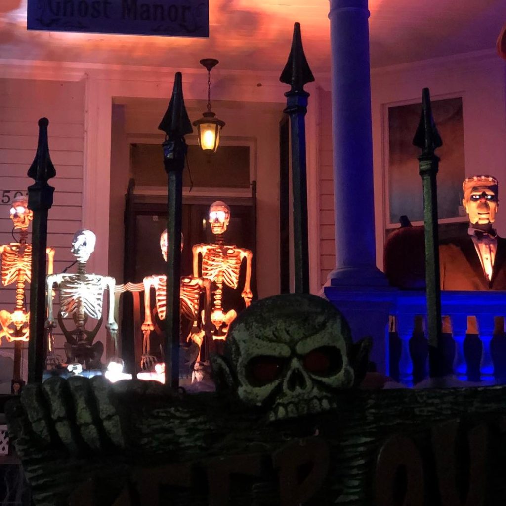 Illuminated skeletons and skull on spooky porch