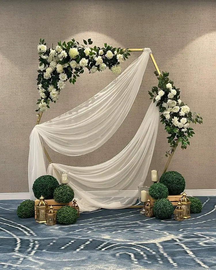 White draped arch with flowers and greenery accents