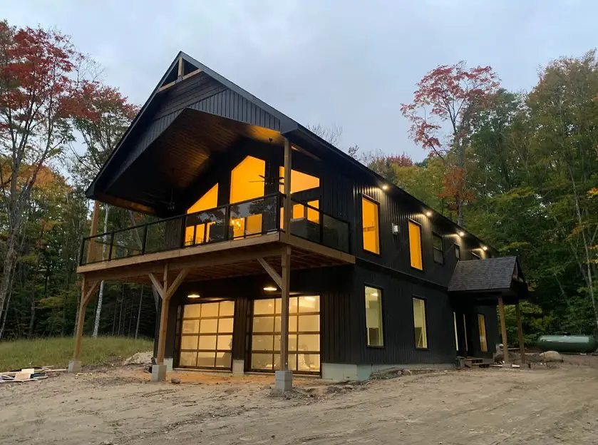 Black modern barn home glowing at dusk