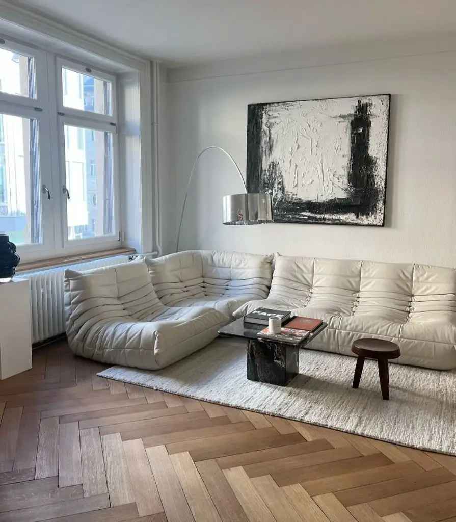 Minimalist white living room with curved sofa and abstract art