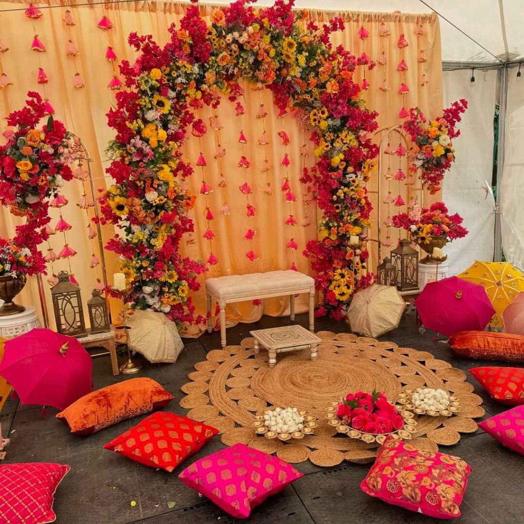 Colorful floral arch with cushions for mehndi ceremony