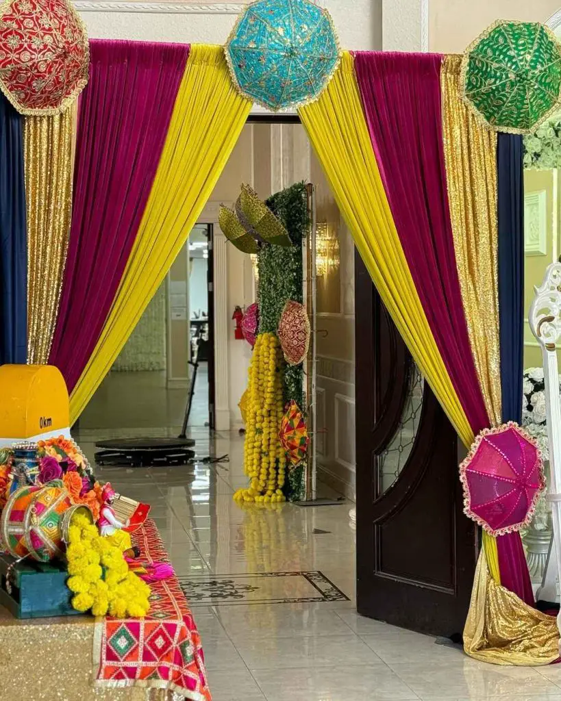 Colorful Mehndi party entrance with umbrellas and drapes