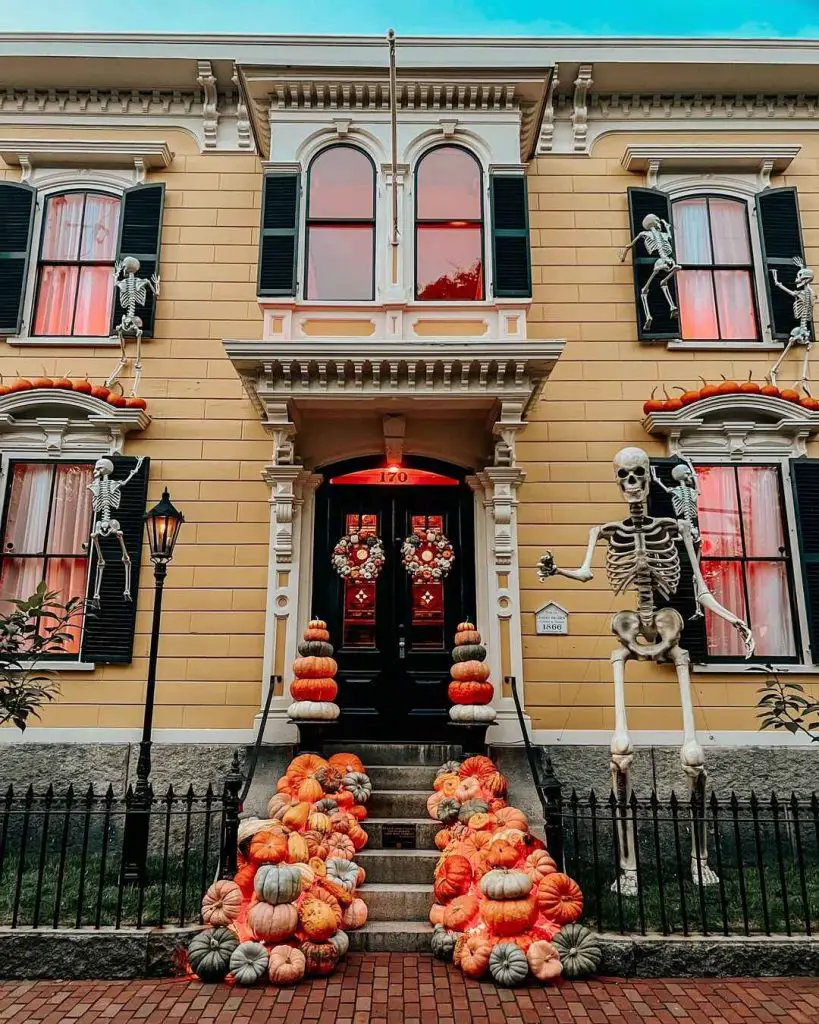 Victorian house with skeletons and pumpkin decor.