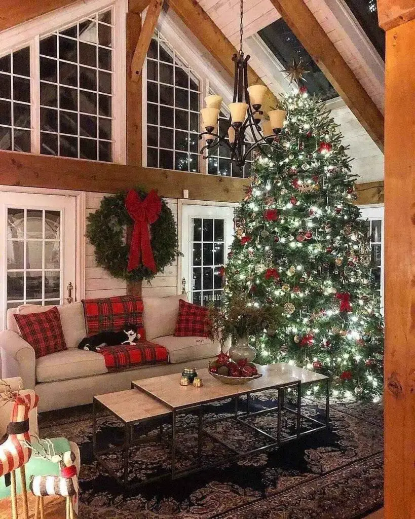 Decorated Christmas tree and stockings by lit fireplace.