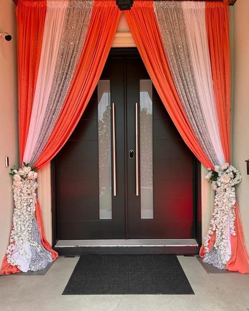 Double doors with pink flowers and chandeliers welcome guests.