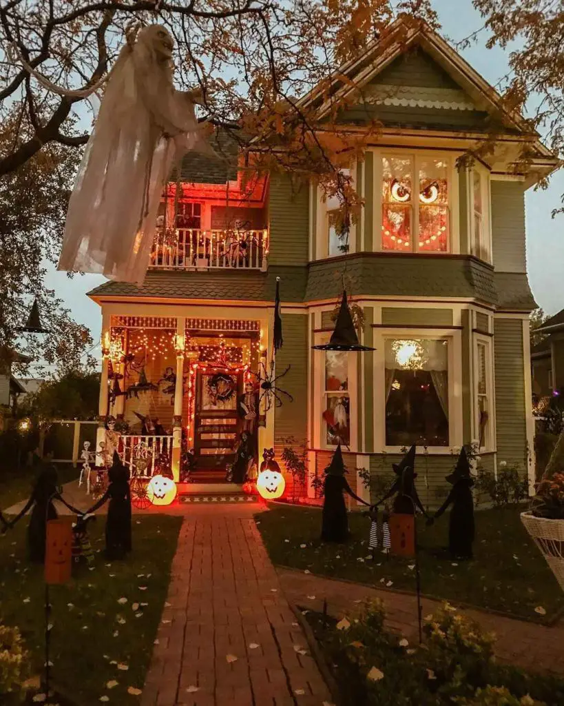 Victorian house decorated for Halloween with ghost and lights