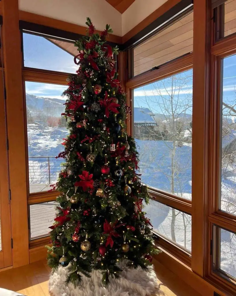 Christmas tree with red decorations overlooking snowy mountains