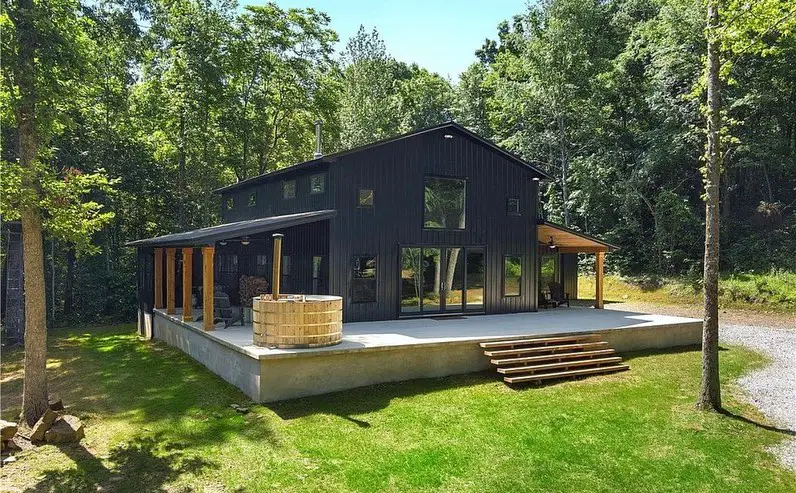 Modern black barndominium with forest backdrop