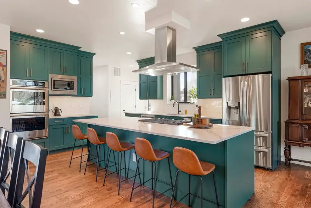 Modern green kitchen with leather barstools and white counters