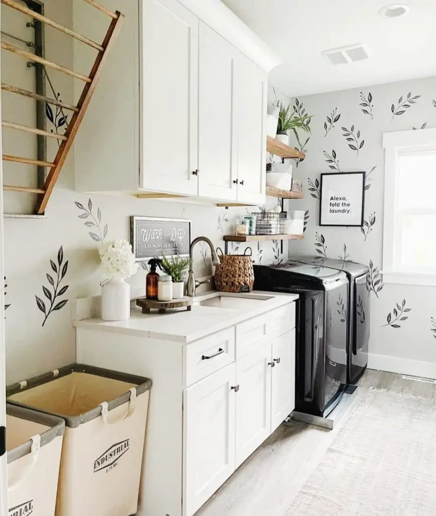 Modern farmhouse laundry room with leaf wallpaper and white cabinets