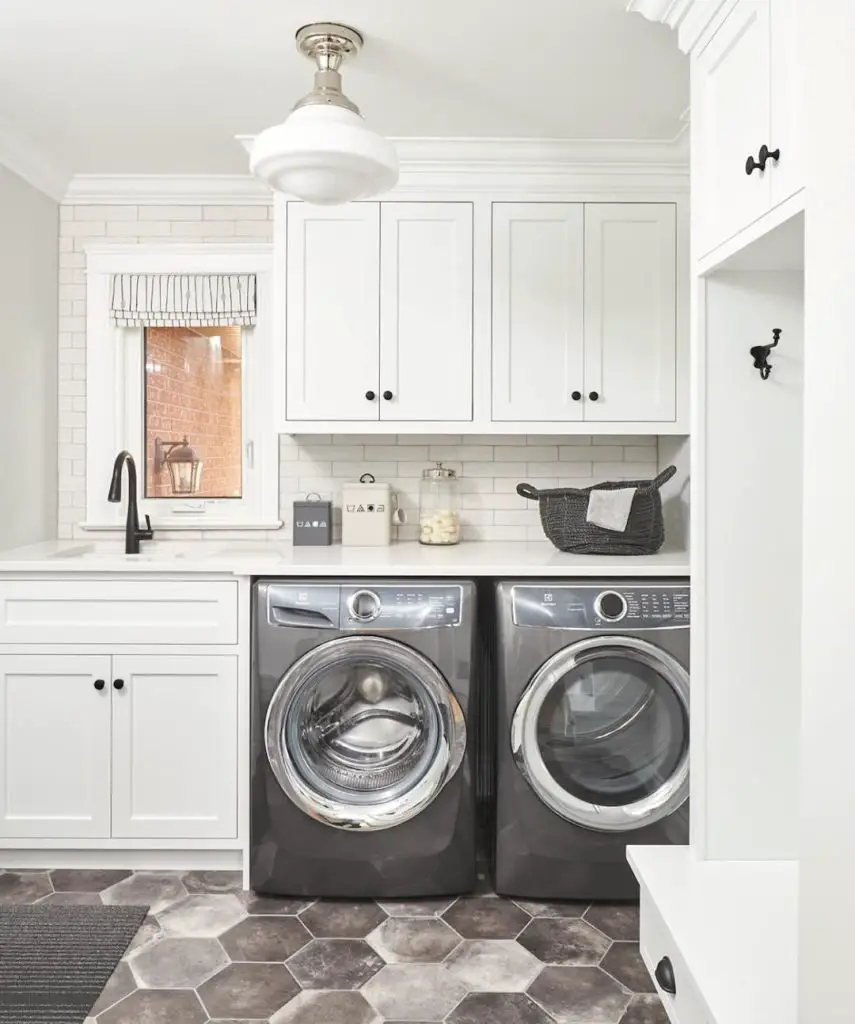 Modern white laundry room featuring hexagon floor tiles and sleek gray appliances
