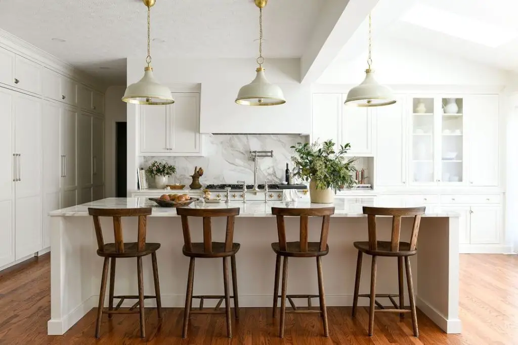 Bright white kitchen with wooden barstools and pendant lights