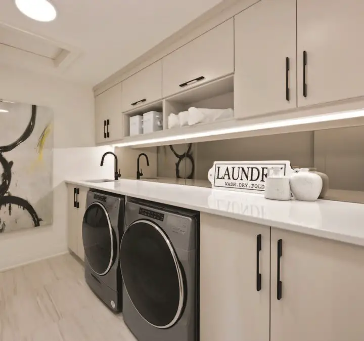 Modern white laundry room featuring LED lighting built-in shelving and abstract artwork