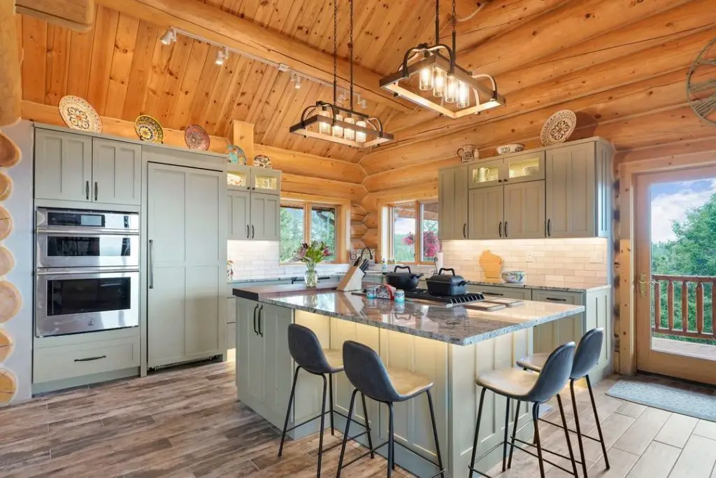 Log cabin kitchen with sage cabinets and pine ceiling