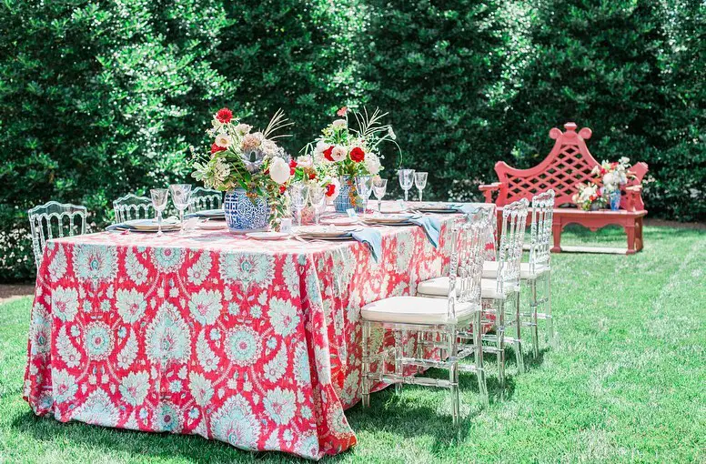 Garden party table with coral ikat tablecloth crystal chairs and chinoiserie floral arrangements