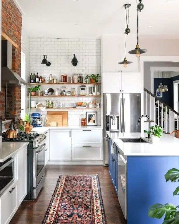 Industrial kitchen with blue island and brick accent wall"