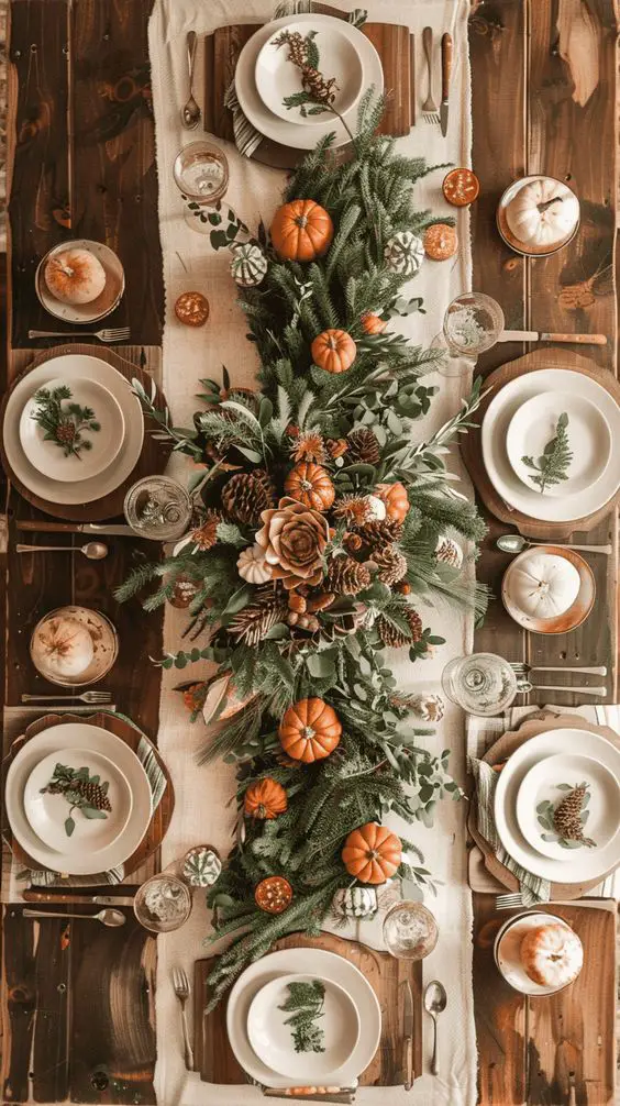 Rustic table setting featuring evergreen garland with scattered pumpkins and botanical plate designs on cream runner