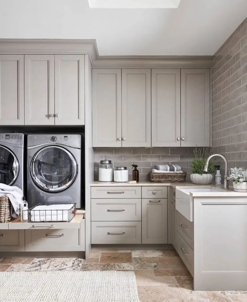L-shaped taupe laundry room with skylight and stone floors