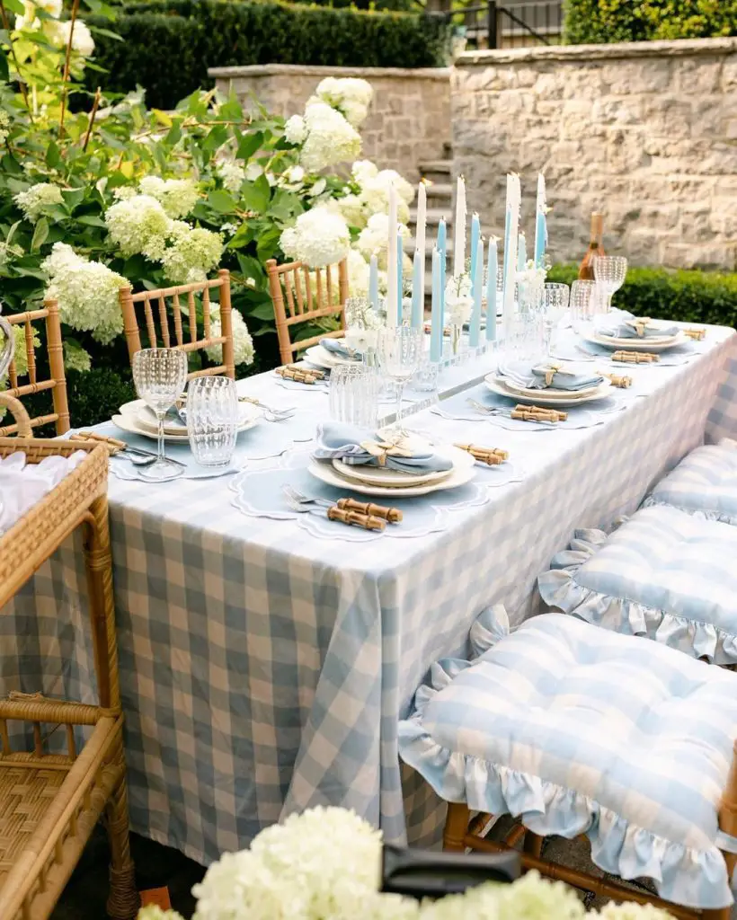 Blue gingham tablescape with white hydrangeas and bamboo accents in garden setting