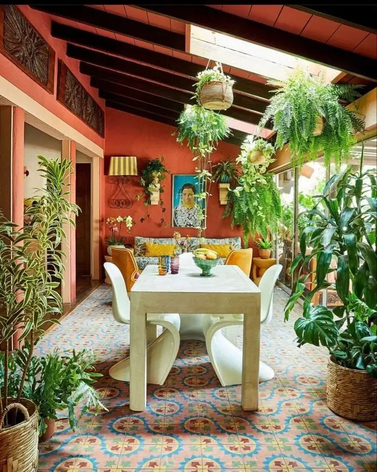 Modern dining area with hanging ferns terra cotta walls and patterned tiles in Mexican-inspired sunroom